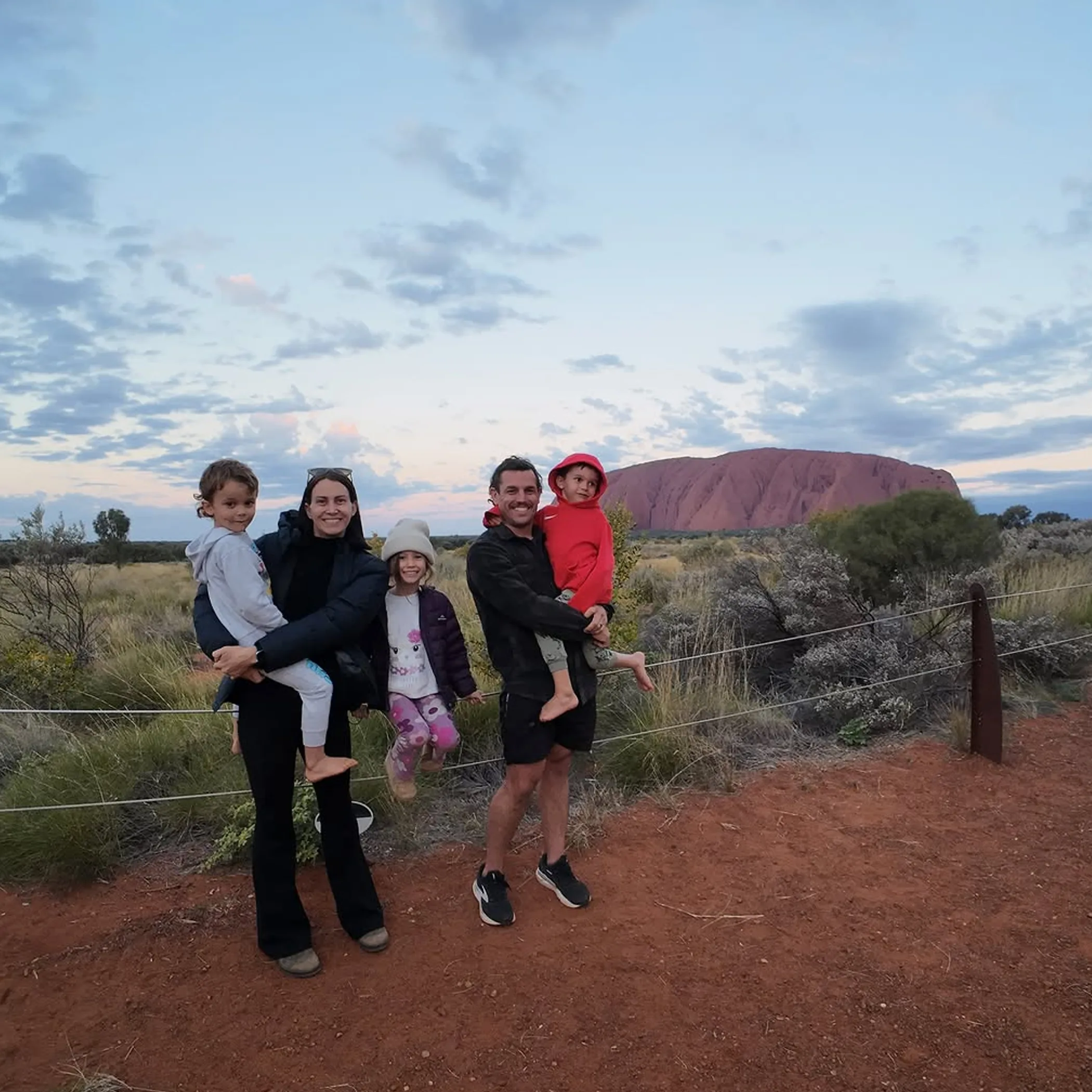 travellers wearing wide brim hats walking uluru
